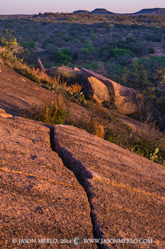Last light on an exfoliation crack and boulders on Buzzard's Roost at Enchanted Rock State Natural Area in Llano County in the...