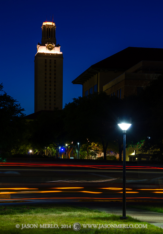 Light streaks from a moving bus under the Tower darkened for UT Remembers at twilight at the University of Texas in Austin, Texas...