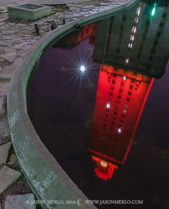 The Tower lit orange for the 2014 Distinguished Alumni Awards reflected in the Turtle Pond at the University of Texas in Austin...