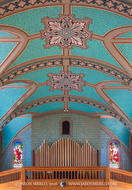 The organ pipes are flanked by stained glass windows under the intricately painted ceiling at Immaculate Heart of Mary Church...